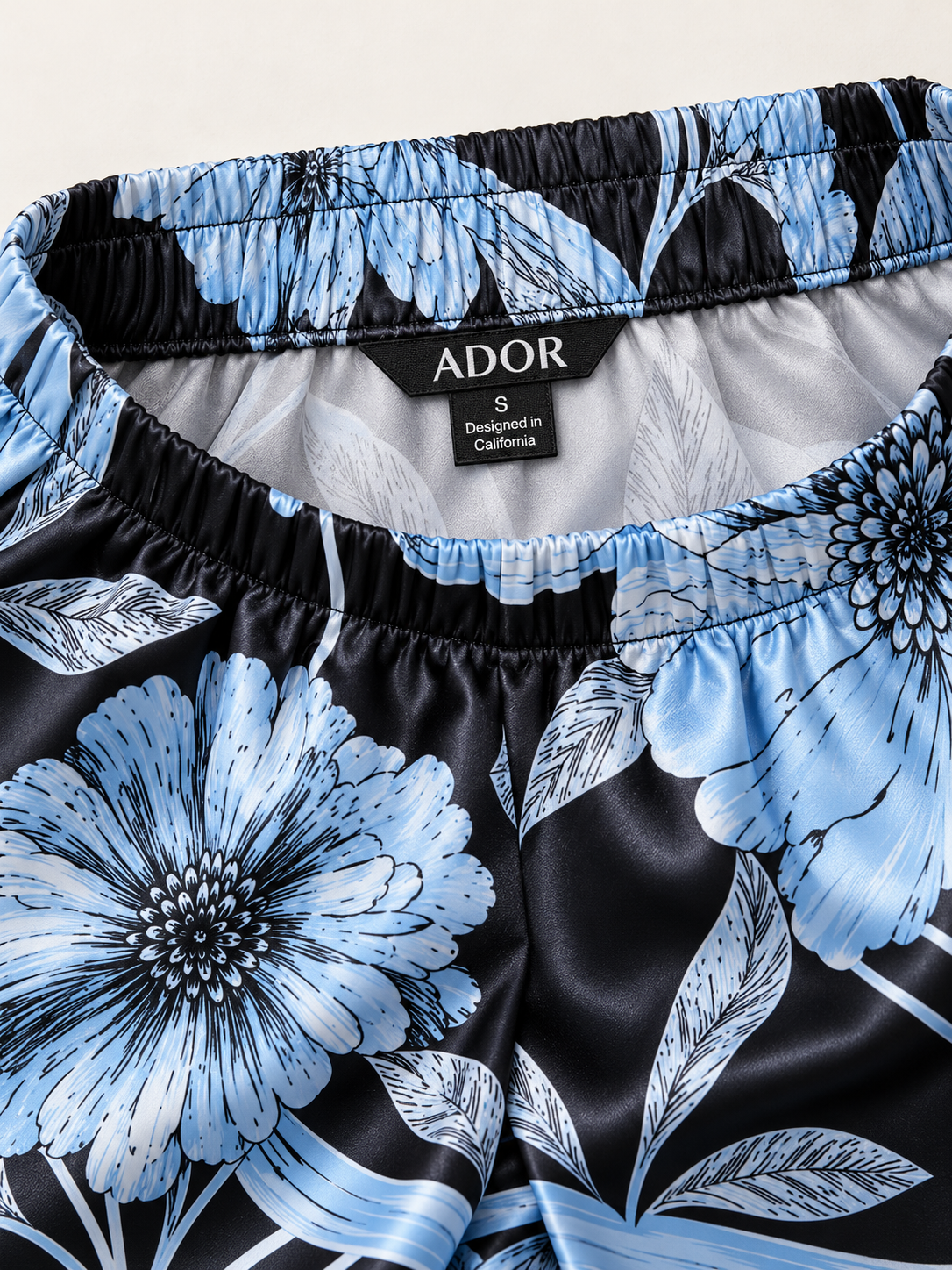 ADOR brand label detail on Glacier Blue Petal Silky Satin Wide Leg Pants
